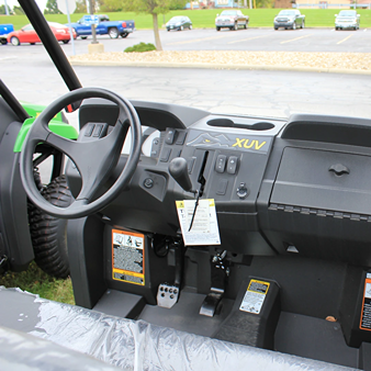 Interior view of John Deere utility vehicle featuring steering wheel, control panel, and rugged design elements