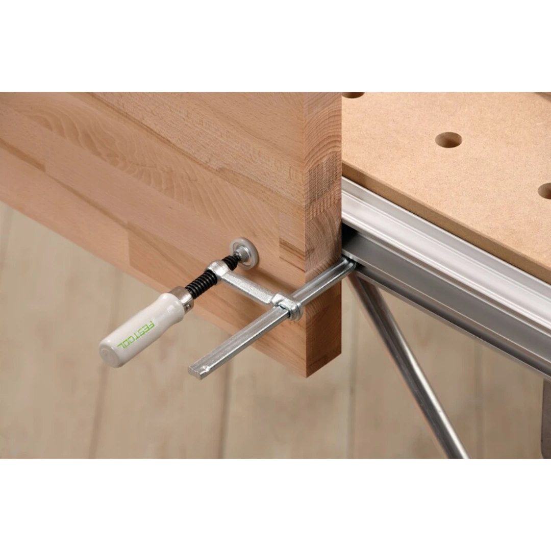 Metal screw clamp with white handle securing wooden piece to workbench in woodworking tool accessories collection