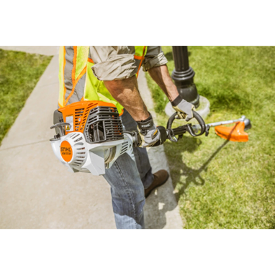 Person wearing safety vest using a STIHL KM 111 R KombiMotor for outdoor lawn maintenance tasks