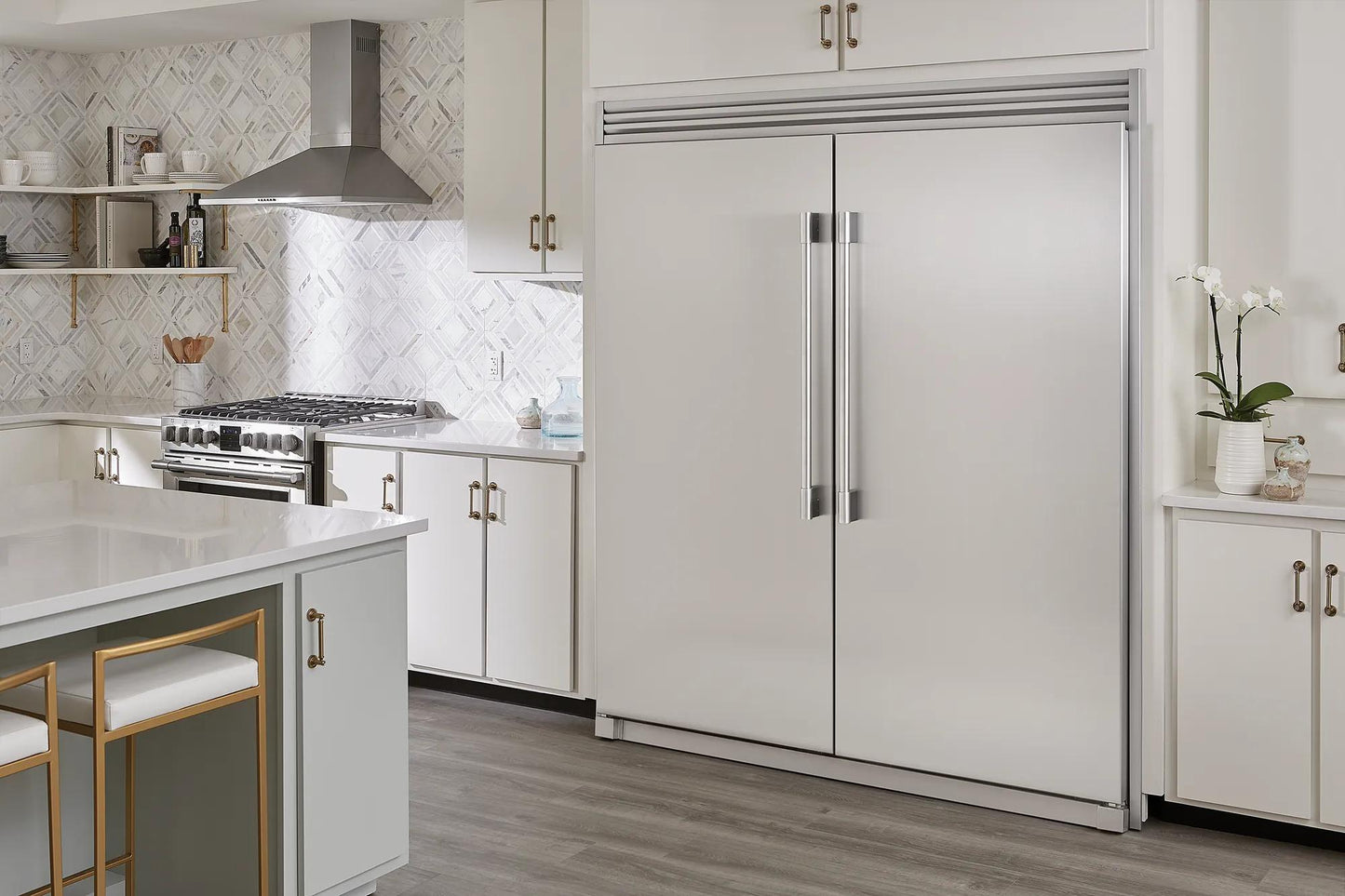 Built-in stainless steel double-door freezer in a modern kitchen setting with white cabinetry and hardwood floors