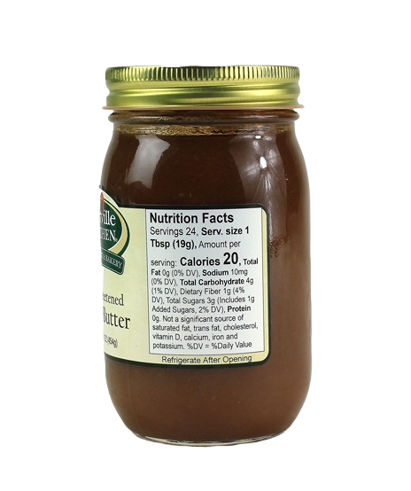 Glass jar of unsweetened apple butter with gold lid and nutrition facts label on white background