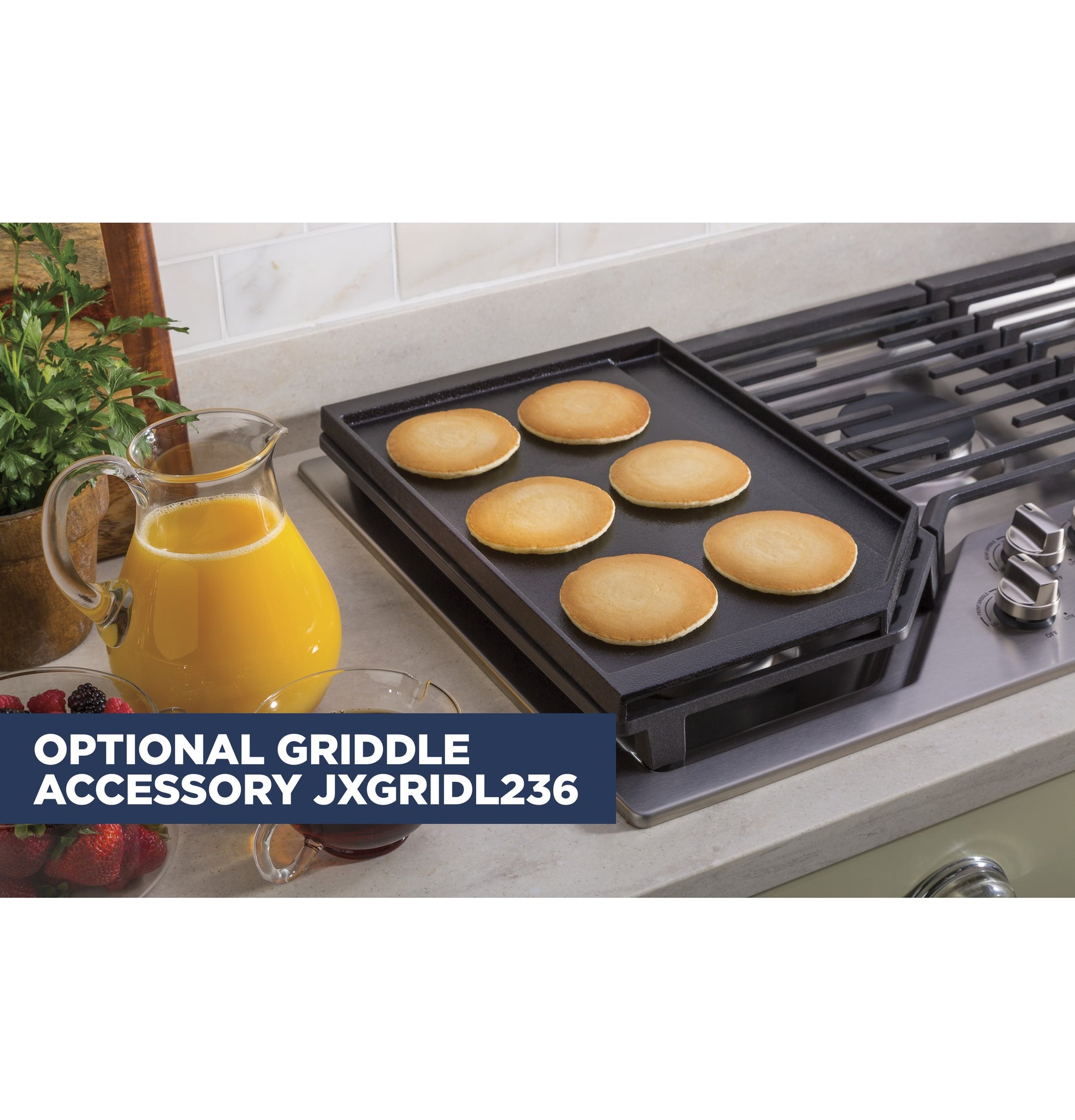 Pancakes cooking on a griddle accessory placed over a five-burner built-in gas cooktop in a modern kitchen setting