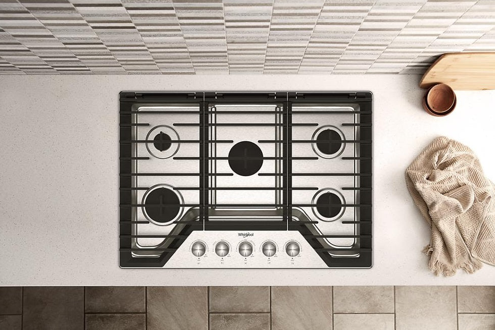 Top-down view of 30-inch gas cooktop with five burners and cast-iron grates installed in modern kitchen countertop