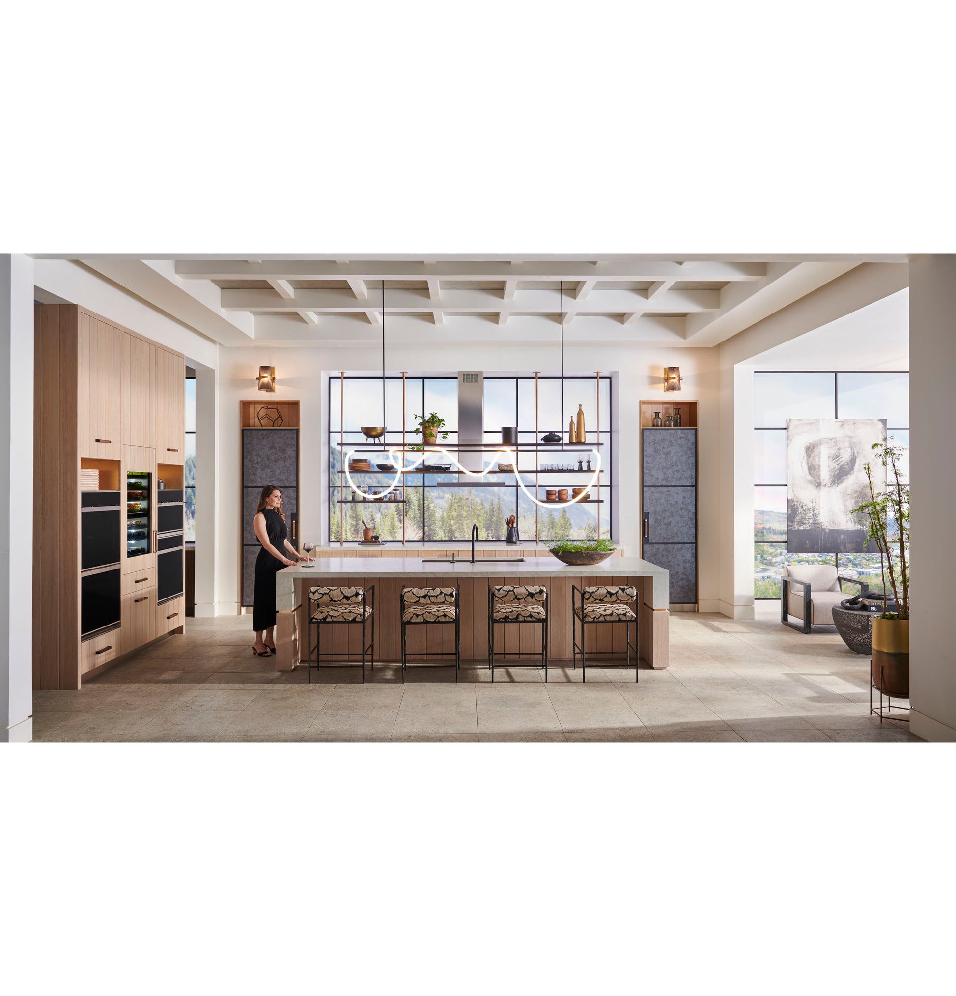 Spacious kitchen with Monogram minimalist double wall ovens, large island, pendant lighting, and scenic window views in appliances collection