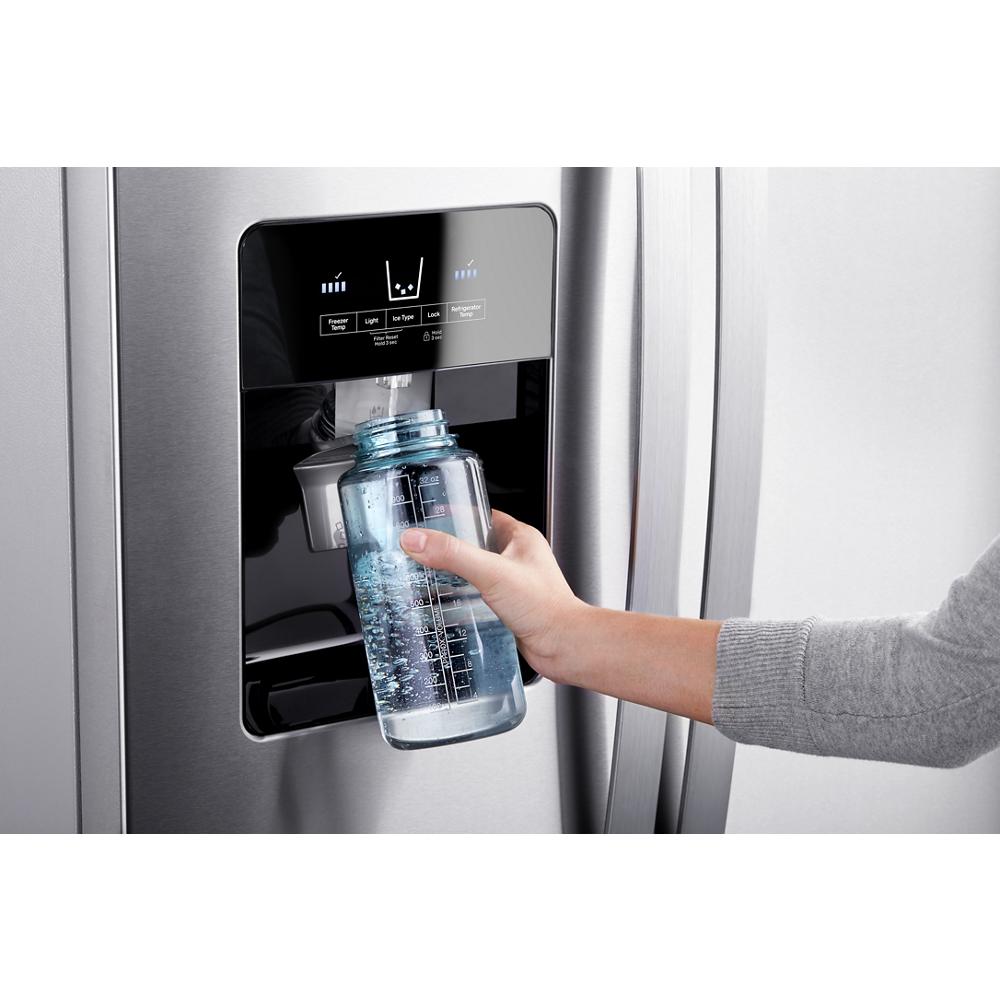 Hand filling a glass bottle with water from a stainless steel refrigerator ice and water dispenser in kitchen appliances collection