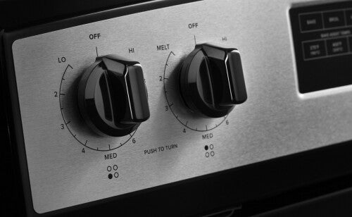 Close-up of black control knobs on stainless steel panel with temperature settings for electric range burners and bake modes