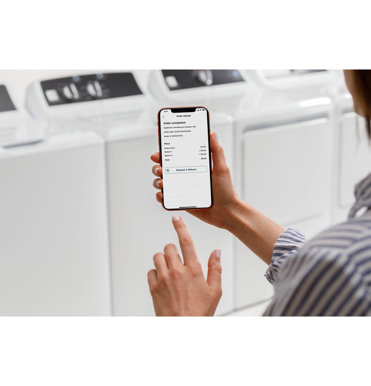 Person using smartphone app to manage laundry payment in front of white commercial top load washers from washers collection