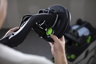 Hand adjusting green control knob on black Festool drywall sander for precise home improvement tasks