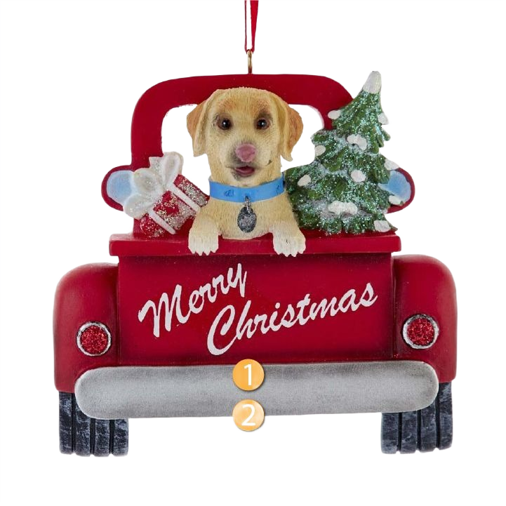 Yellow Labrador dog with blue collar in red truck holding Christmas tree and gift ornament