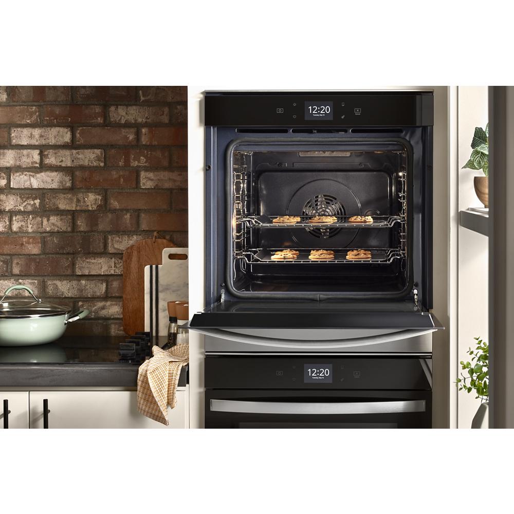 Black double wall oven with convection baking multiple small dishes inside in modern kitchen setup with brick backsplash