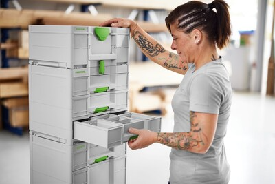 Woman organizing tools in a white and green Festool modular drawer system for workshop storage and tool accessories