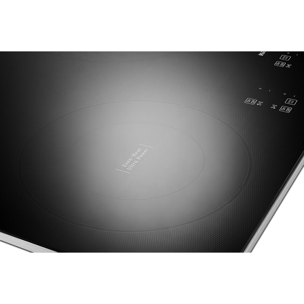 Close-up of black glass electric cooktop with touch controls and multiple heating elements from KitchenAid appliances collection