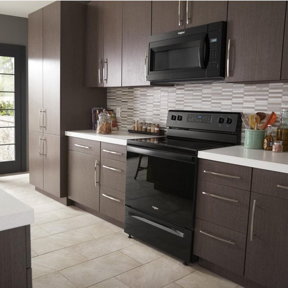 Black over-the-range microwave and electric stove integrated into modern kitchen cabinetry with tile backsplash and countertop cookware