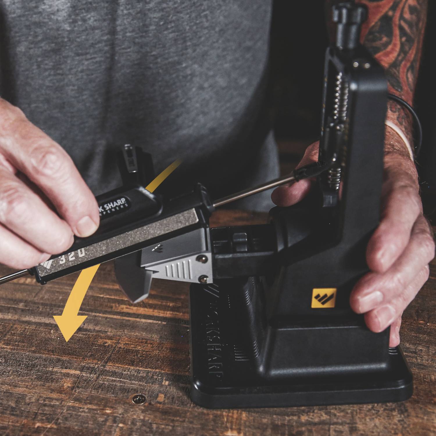 Person sharpening thin blade with Work Sharp Precision Adjust Knife Sharpener on wooden surface for home tool care