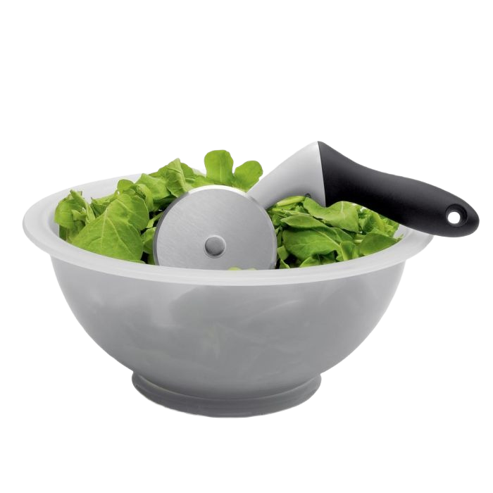 White mixing bowl filled with fresh greens and a black-handled chopper for easy kitchen preparation