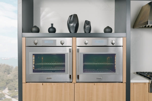 Pair of stainless steel built-in wall ovens with glass doors installed in modern kitchen cabinetry and kitchenware decor