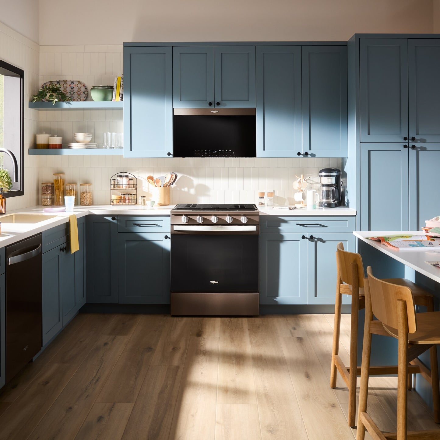 Modern kitchen with blue cabinetry featuring a black air fry over-the-range microwave and matching stainless steel range