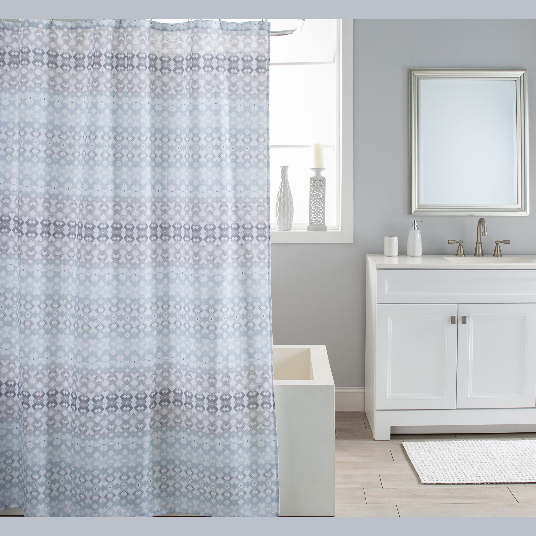 Grey and blue patterned fabric shower curtain hanging in modern bathroom with white vanity and mirror