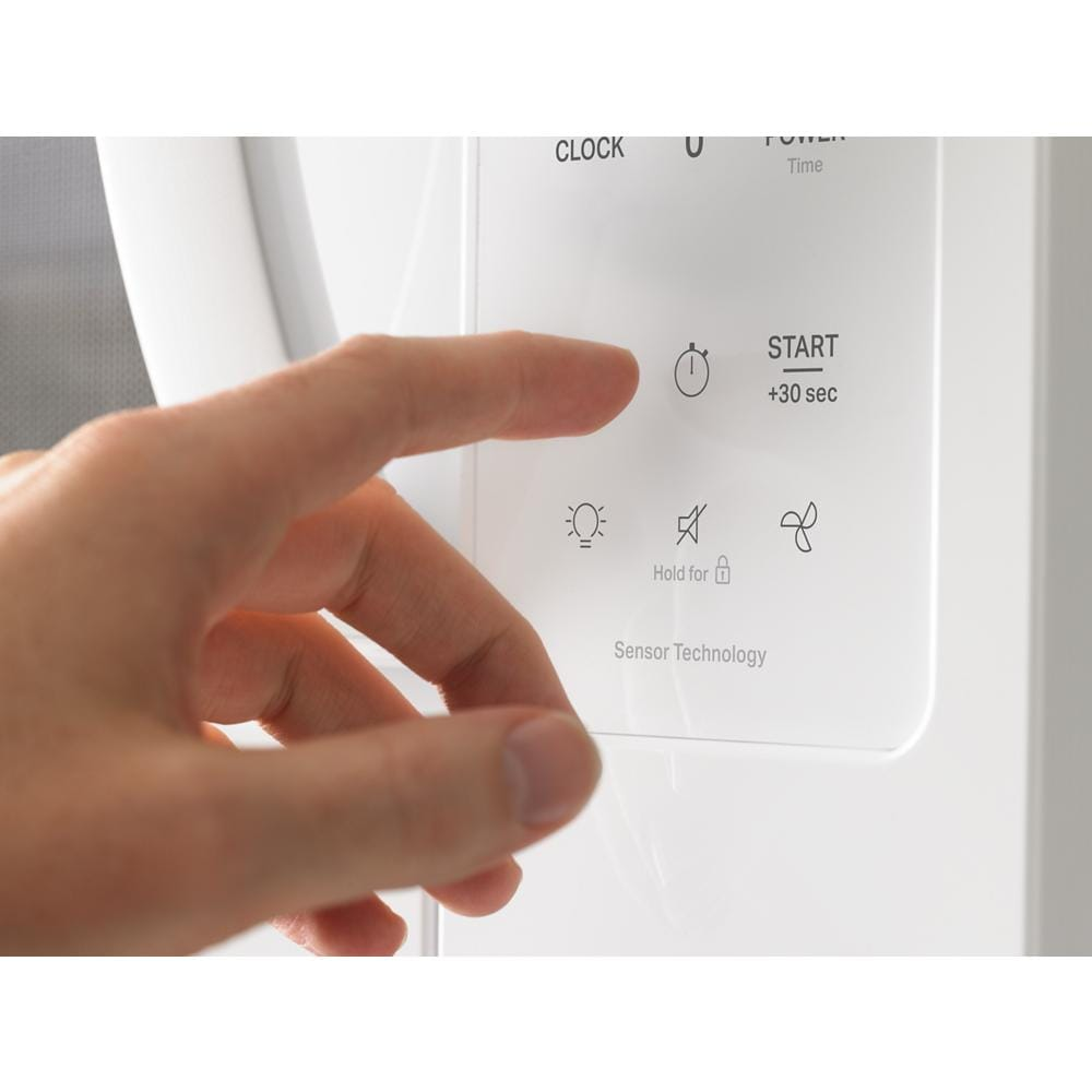 Hand pressing start button on white over the range microwave with sensor technology in kitchen appliances collection