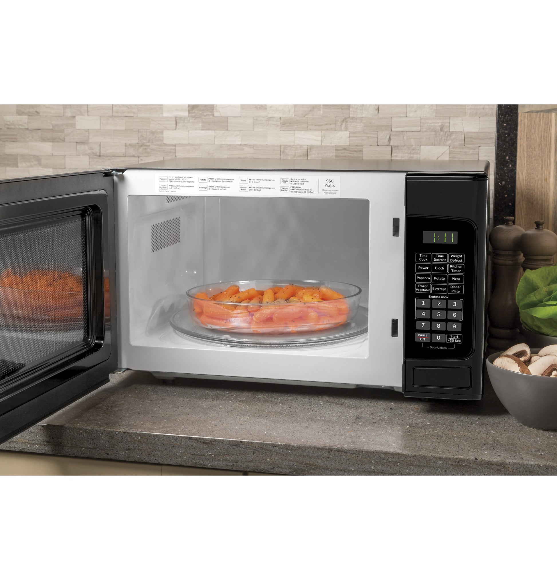 Open black microwave oven with digital control panel cooking a dish of sliced carrots on countertop in kitchen setting