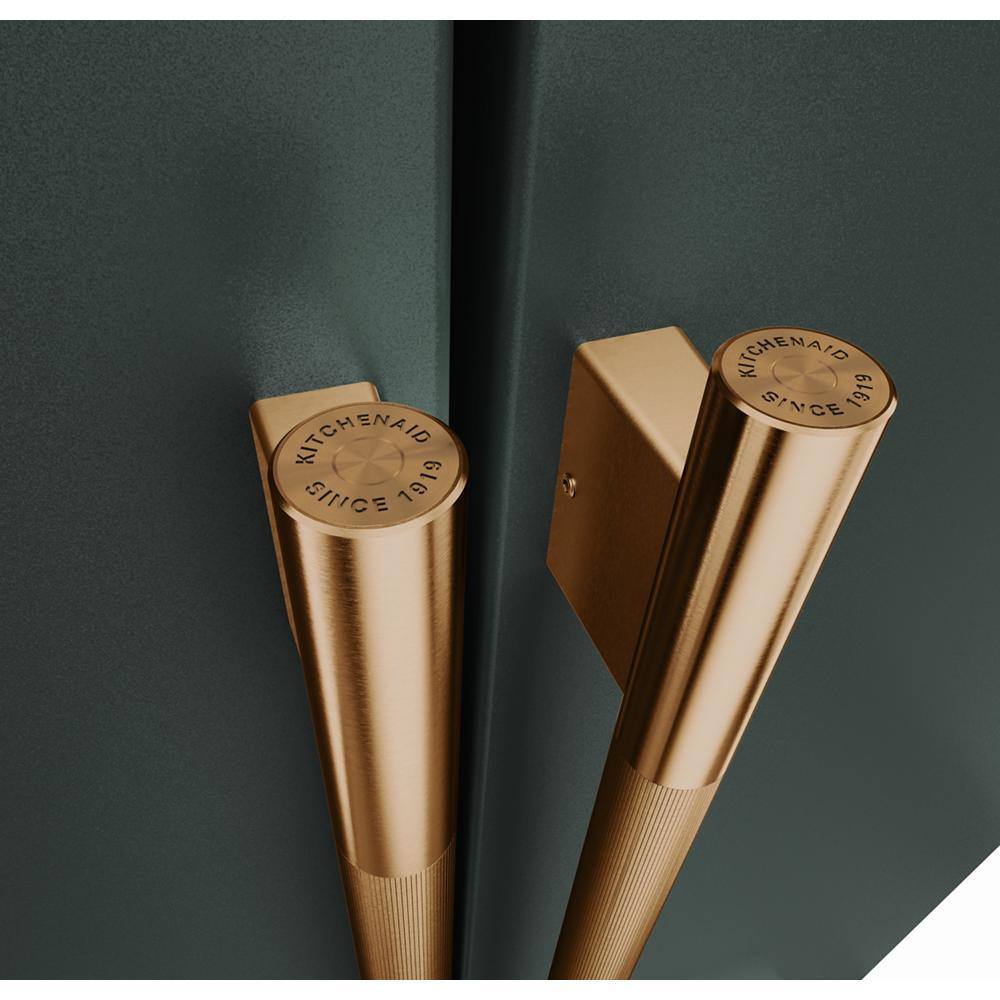 Close-up of brushed gold handles with engraved KitchenAid logo on dark green French door refrigerator doors