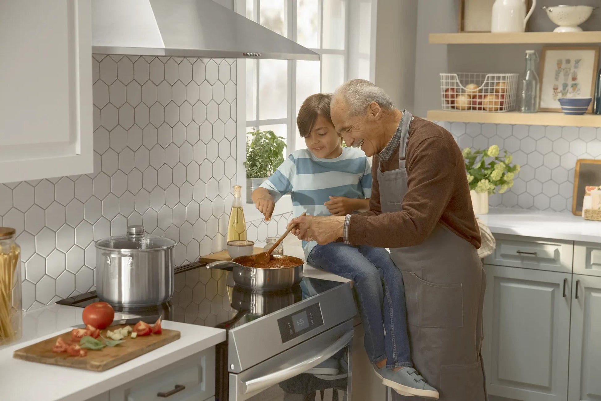 Grandfather and child cooking together using a stainless steel induction range in a modern kitchen setting