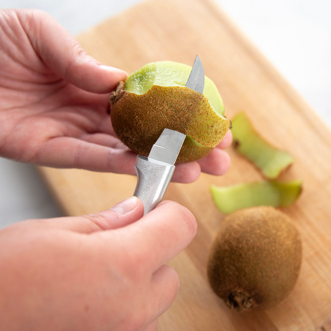 Hands peeling a kiwi with a small paring knife featuring a solid aluminum handle, ideal for Kitchenware, Cooking Utensils, and Under $50 collections.
