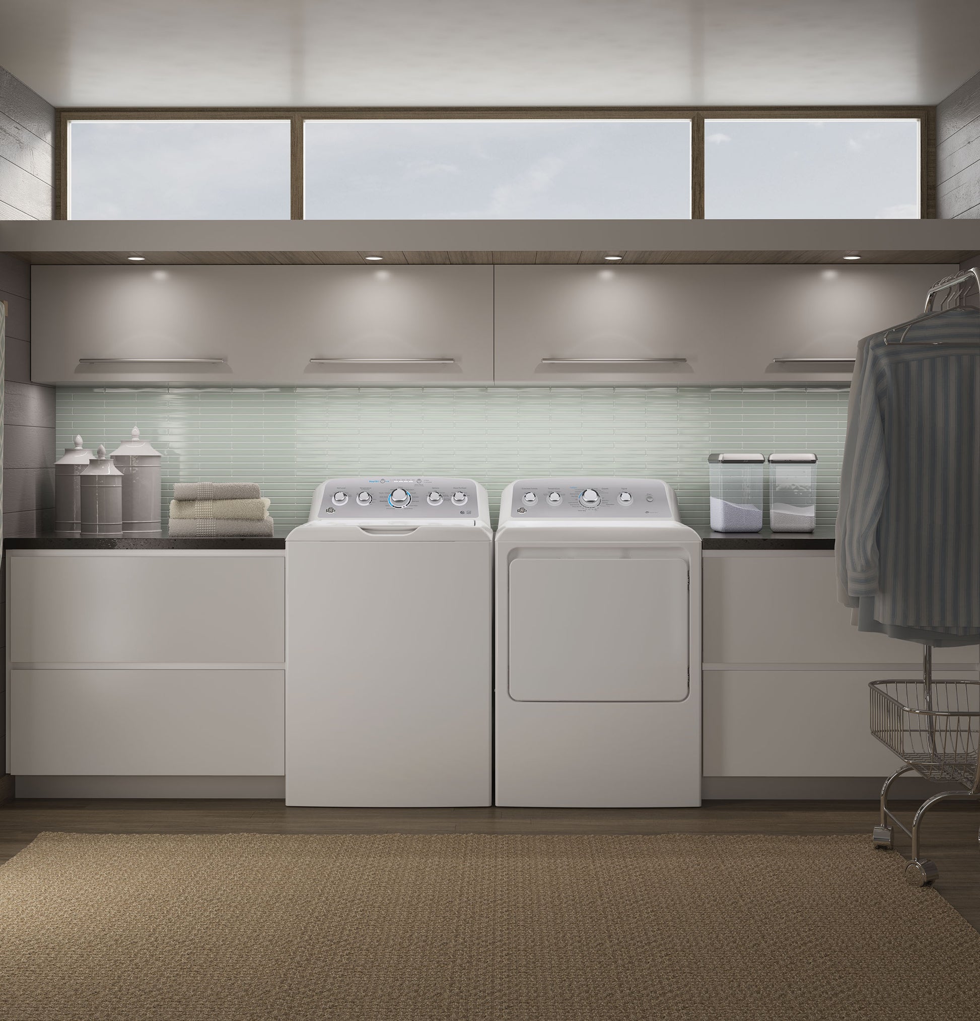 Modern laundry room with white top load washer and dryer set under soft recessed lighting in clean white cabinetry