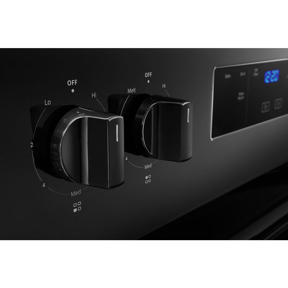 Close-up of black electric range control knobs and digital timer display in kitchen appliances and ranges collection