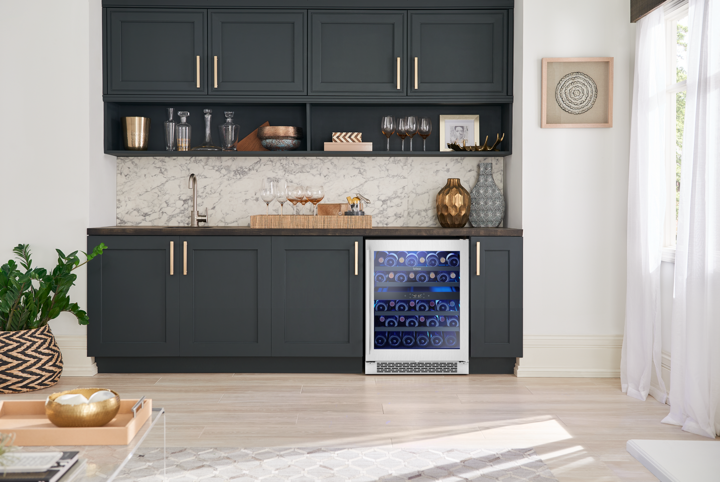 Built-in Brisas wine cooler with stainless steel and glass door, blue LED lighting, and horizontal bottle storage in a modern kitchen and beverage center setting.