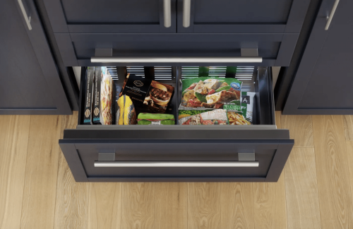 Open bottom freezer drawer with frozen meals stored inside modern built-in kitchen appliance setup