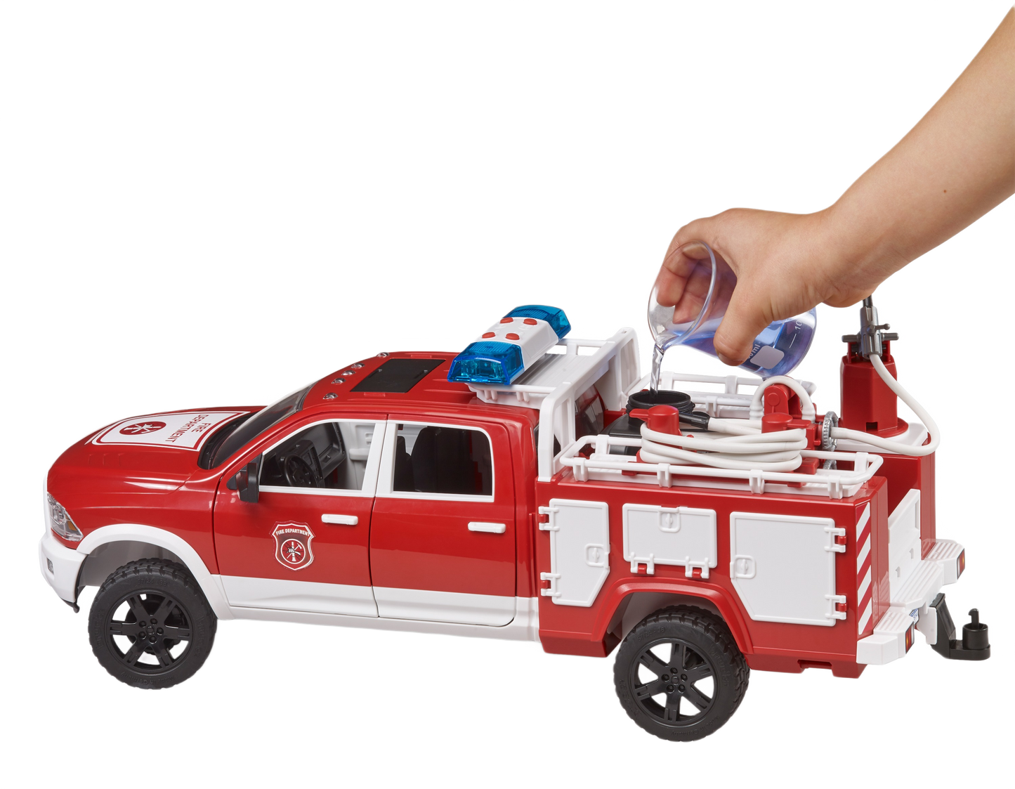 Child’s hand pouring water into a red and white Bruder RAM fire rescue truck toy with hose and light features