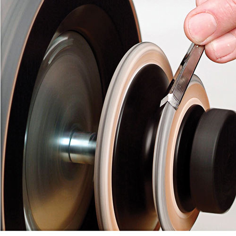 Hand sharpening a blade on a leather honing wheel mounted on a grinding machine for tool maintenance
