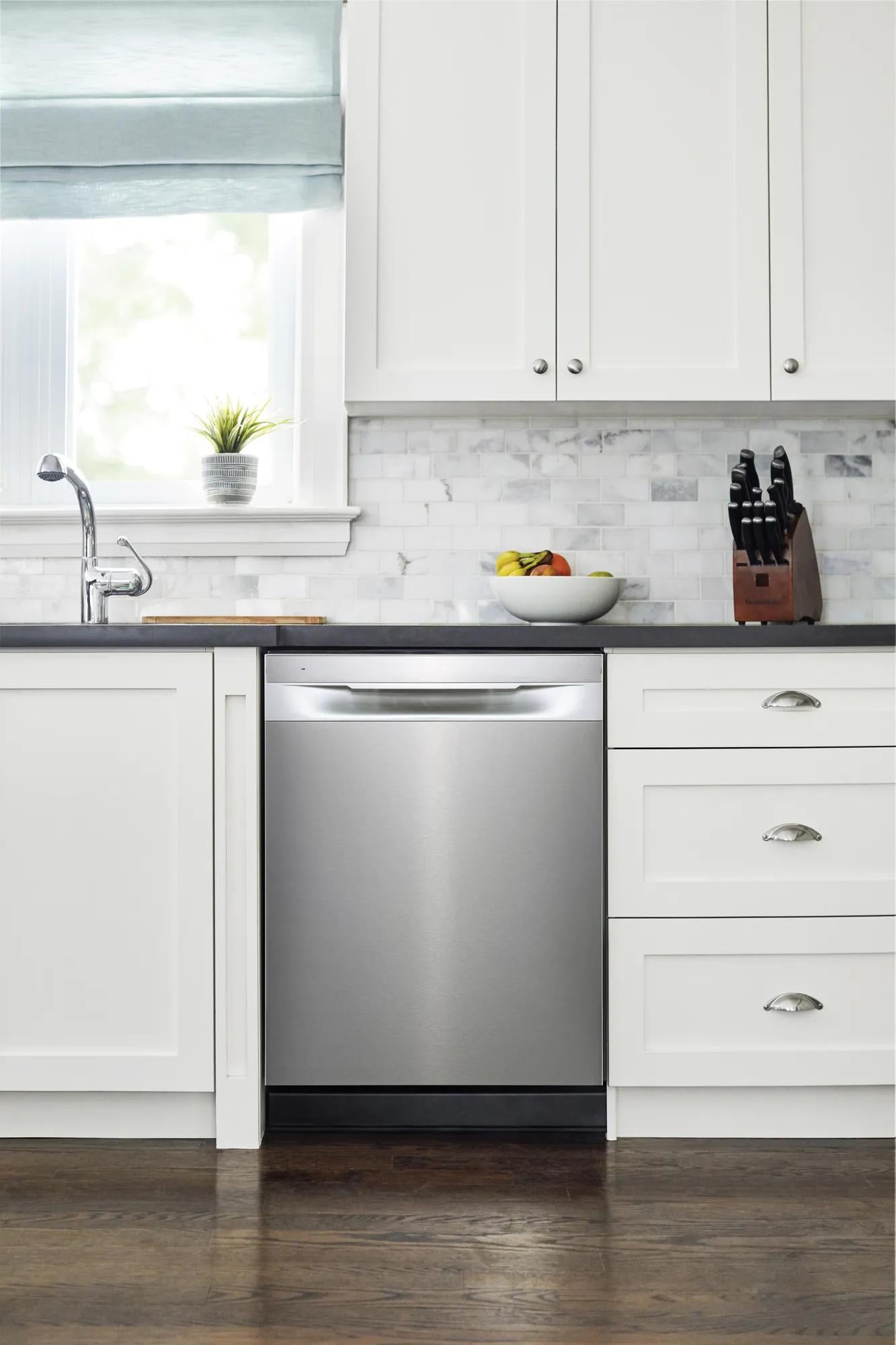 Built-in stainless steel dishwasher integrated into white cabinetry with marble tile backsplash in modern kitchen setting