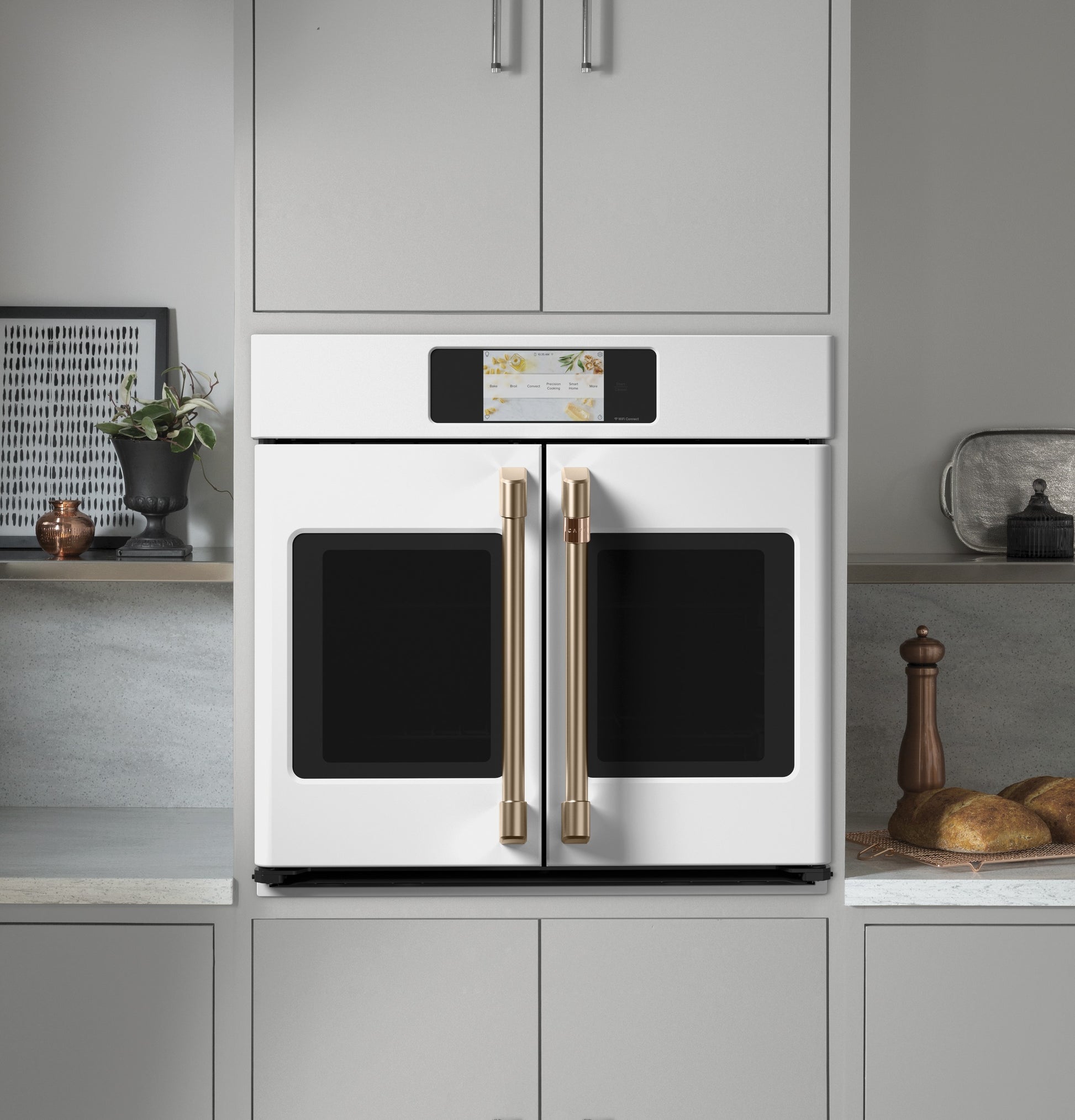 Built-in white double-door wall oven with gold handles and digital touchscreen in modern kitchen setting