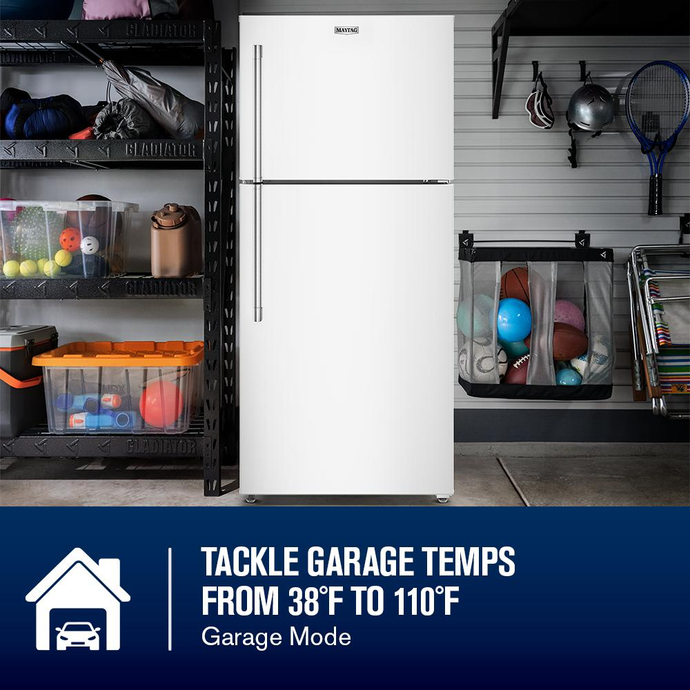 White top-freezer refrigerator with vertical handles in a garage setting featuring sports equipment and storage shelves