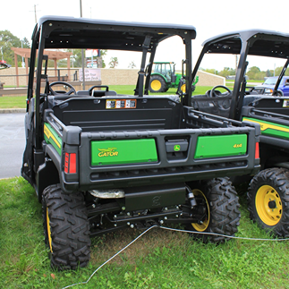 Rear view of a green utility vehicle with rugged custom tires on outdoor grassy display