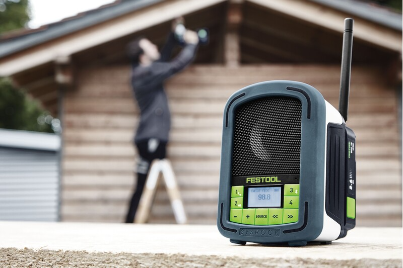 Portable jobsite radio with digital display, green control buttons, and sturdy casing for tools and home improvement use