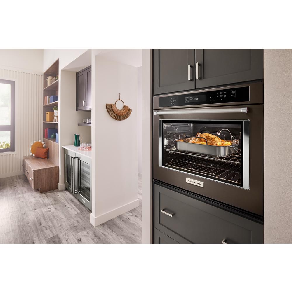 Modern built-in single wall oven in a dark finish roasting chicken inside, part of KitchenAid appliances collection