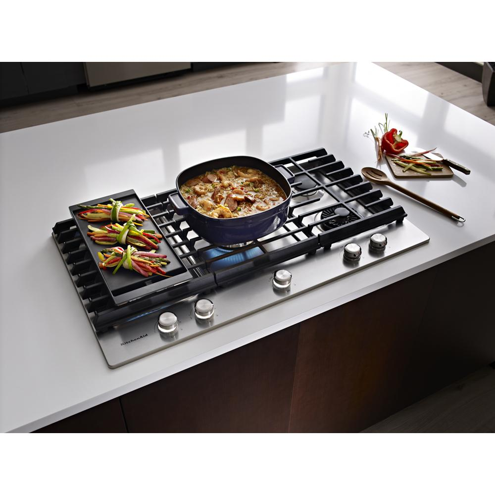 Stainless steel 36-inch gas cooktop with five burners and removable griddle cooking vegetables and stew in kitchen setting