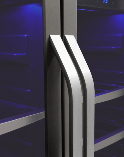 Close-up of stainless steel French door handles on a beverage center with blue interior lighting in kitchen appliances collection