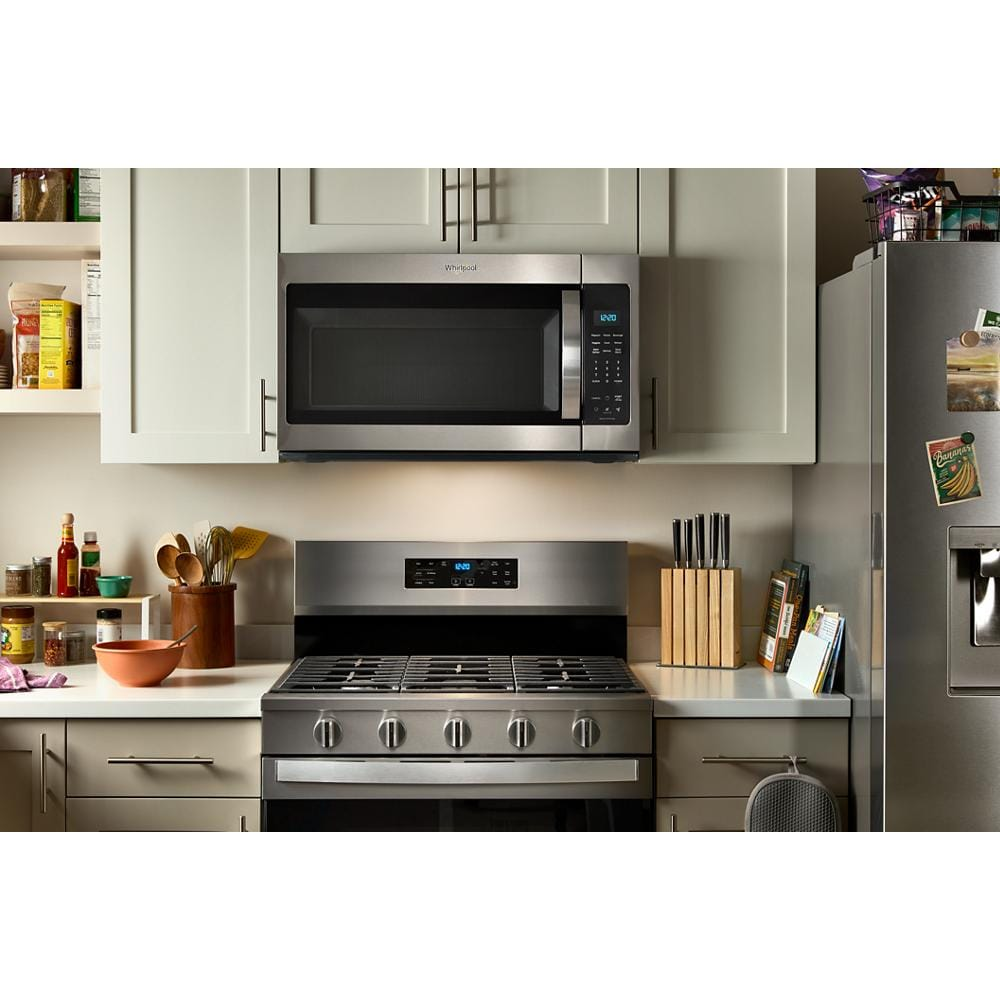 Stainless steel over the range microwave with digital control panel installed above a gas stove in modern kitchen setting