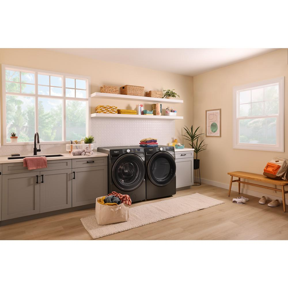 Bright laundry room with dark gray front load washer and gas dryer, beige walls, gray cabinets, and natural light in appliances collection