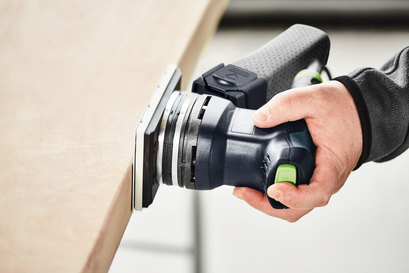 Handheld electric sander with ergonomic grip smoothing the edge of a wooden board in a home improvement setting