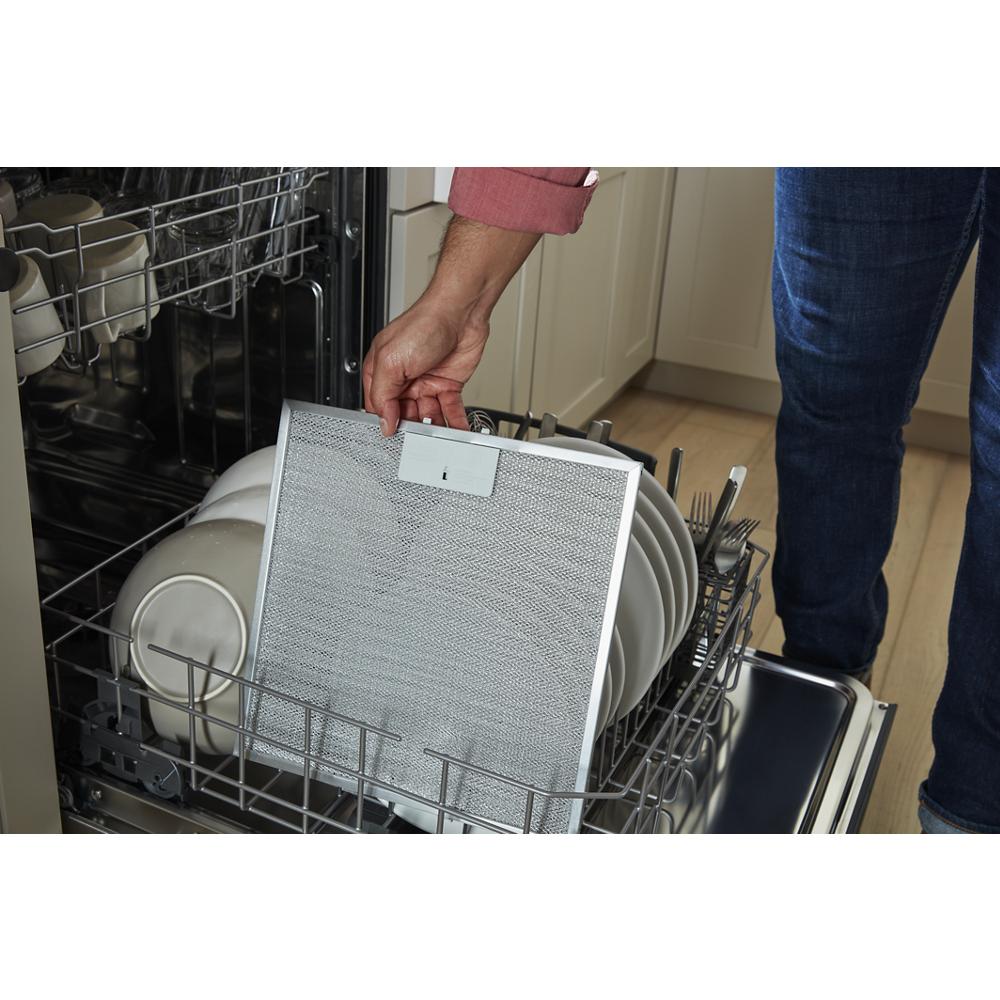 Person removing a dishwasher-safe grease filter from dishwasher rack in kitchen and appliance setting