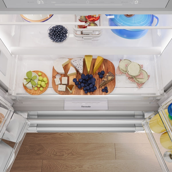 Interior view of stainless steel French door refrigerator with organized fresh produce and cheese platters in kitchen appliance collection