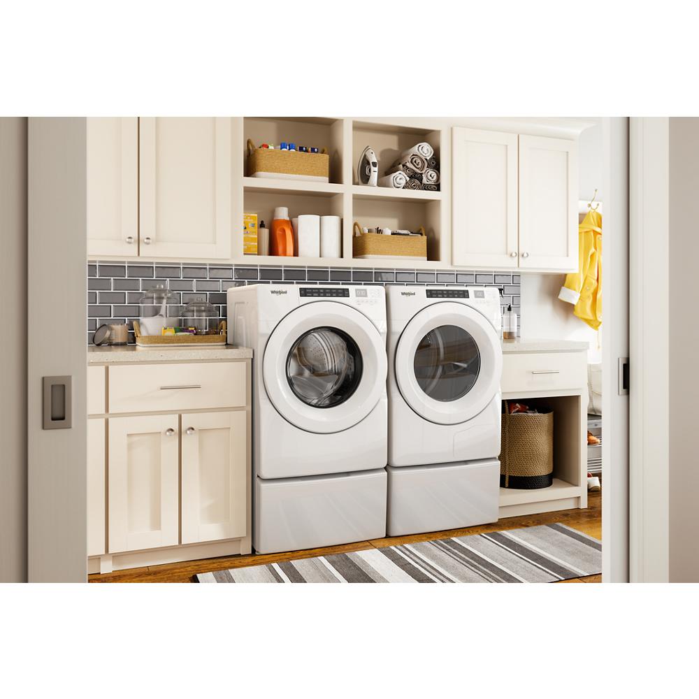 White front load washer and 7.4 cu.ft heat pump dryer in bright laundry room with cabinetry and countertop space