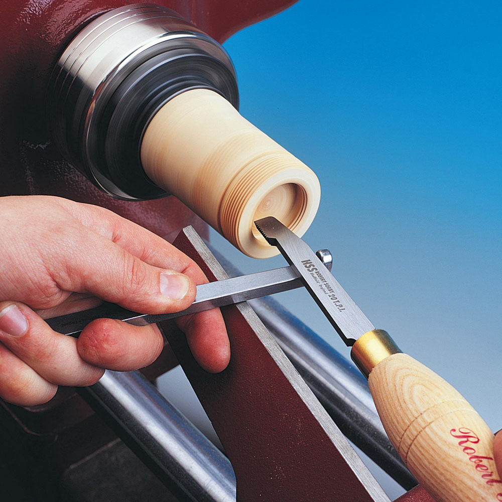 Woodworker using Sorby thread cutting tool to create detailed screw threads on a wooden piece in workshop tools collection