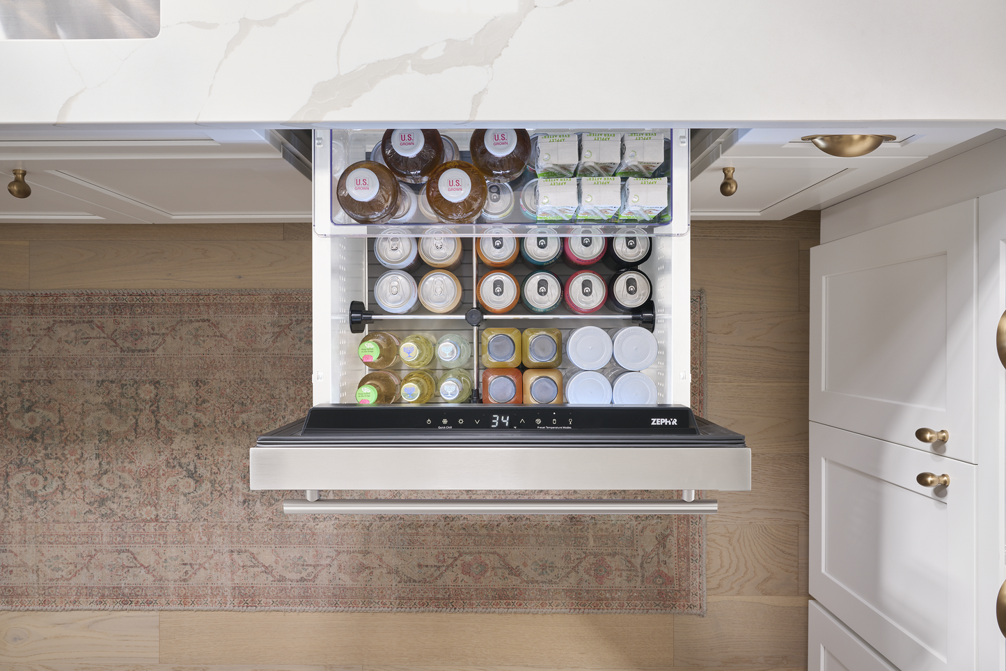 Open stainless steel single zone refrigerator drawer stocked with beverages and food in a modern kitchen setting