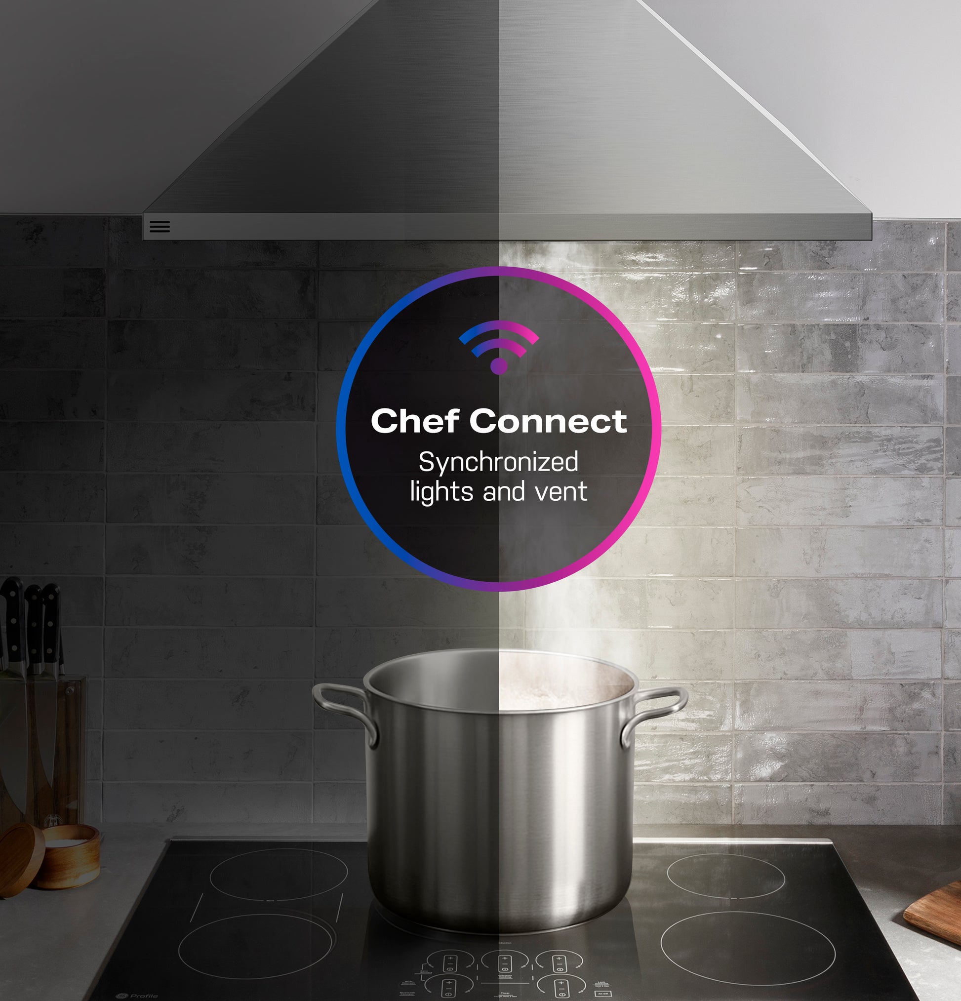 Stainless steel wall-mount pyramid vent hood with clean air sensors and synchronized lights above stovetop in modern kitchen